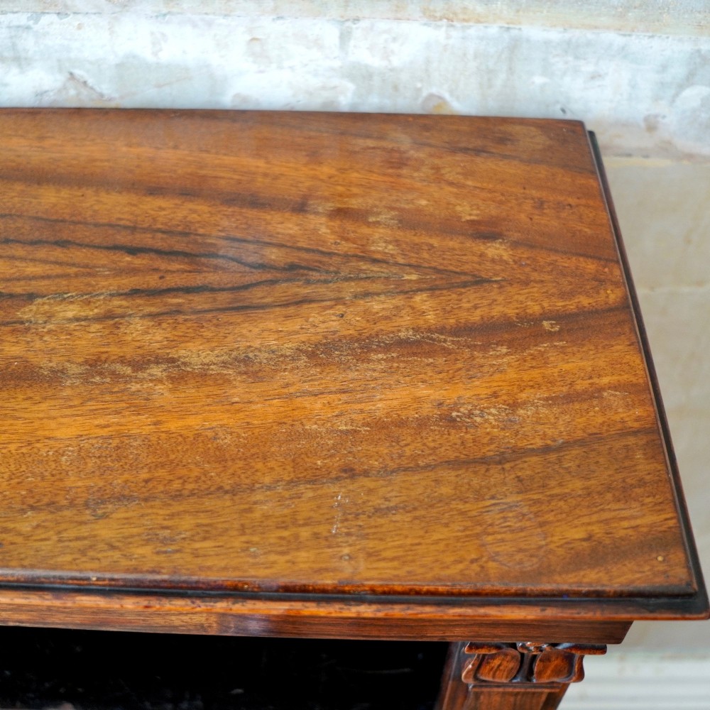 An antique William IV rosewood open bookcase featuring two adjustable shelves, a solid plinth base, and carved scroll capitals atop side pilasters. View VIII