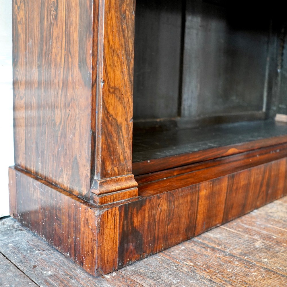 An antique William IV rosewood open bookcase featuring two adjustable shelves, a solid plinth base, and carved scroll capitals atop side pilasters. View IX