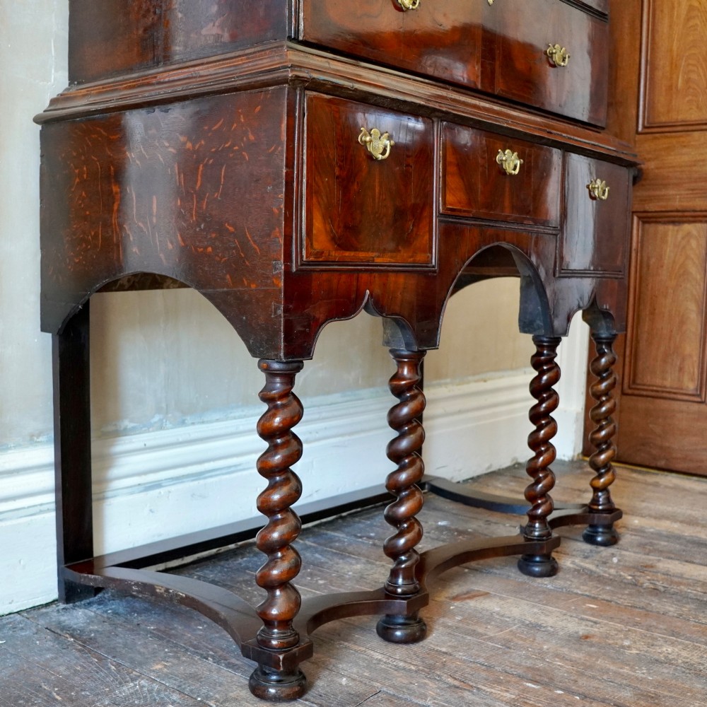 A George I period figured walnut chest on stand featuring engraved brass escutcheons and six barley-twist legs. View IV