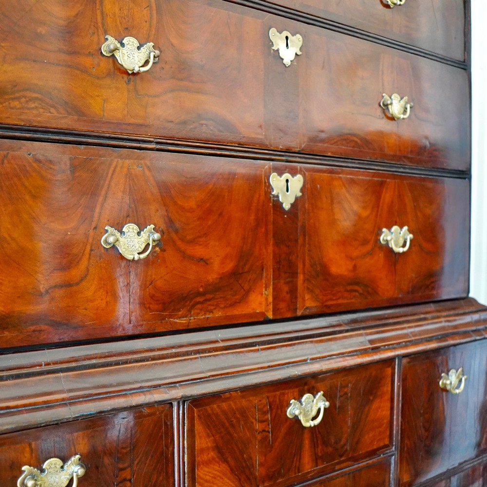 A George I period figured walnut chest on stand featuring engraved brass escutcheons and six barley-twist legs. View V