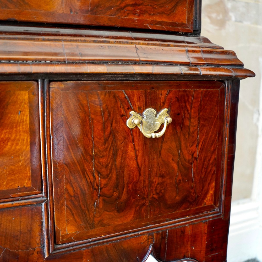A George I period figured walnut chest on stand featuring engraved brass escutcheons and six barley-twist legs. View X
