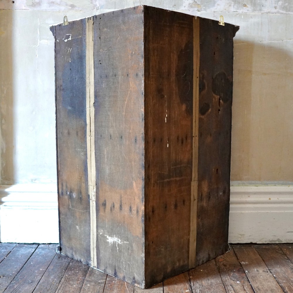 A dark oak George III wall-hanging corner cupboard featuring an arched fielded panel door, moulded cornice, and brass escutcheon. View IX