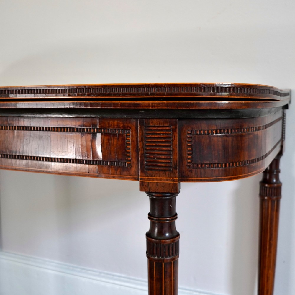 An antique Regency rosewood fold-over card table featuring burr yew crossbanding, a rectangular top with rounded corners, and slender fluted tapered legs. View VIII