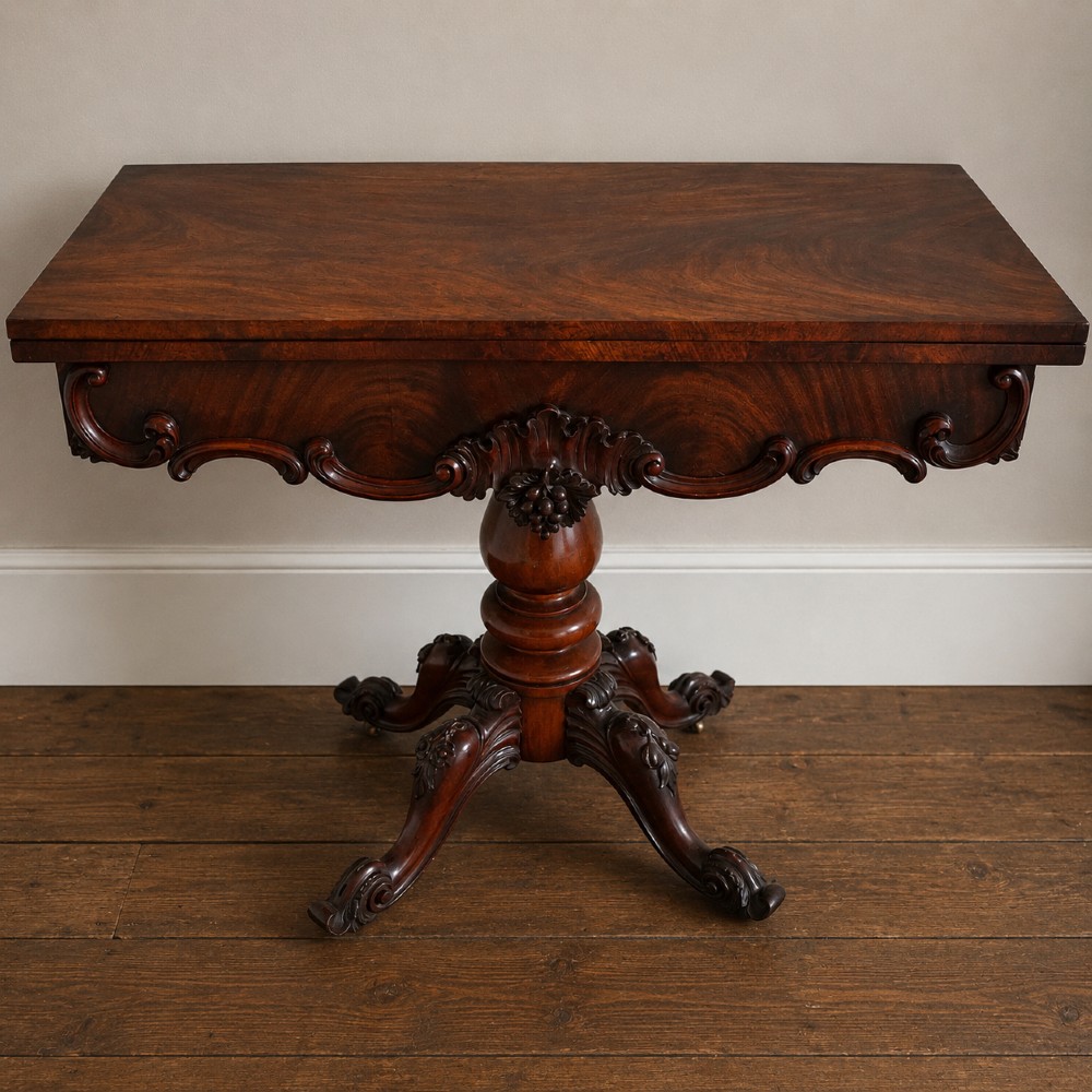 A Victorian figured mahogany card table featuring a turnover top, carved frieze, turned pedestal, and scroll legs with castors.