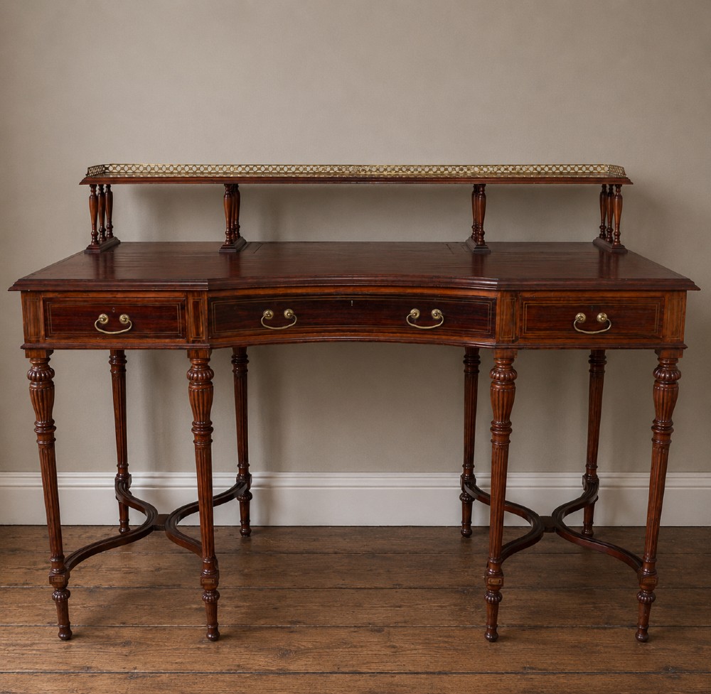 A Victorian rosewood writing desk featuring an upper brass gallery shelf, three frieze drawers with brass handles, fluted legs, and curved stretchers.