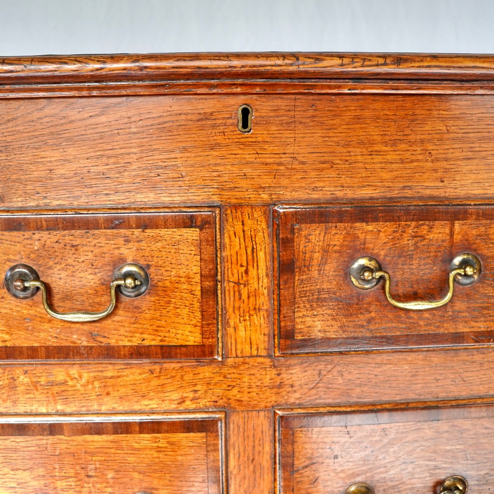A Georgian oak and mahogany crossbanded Lancashire mule chest with brass handles and bracket feet. View XI