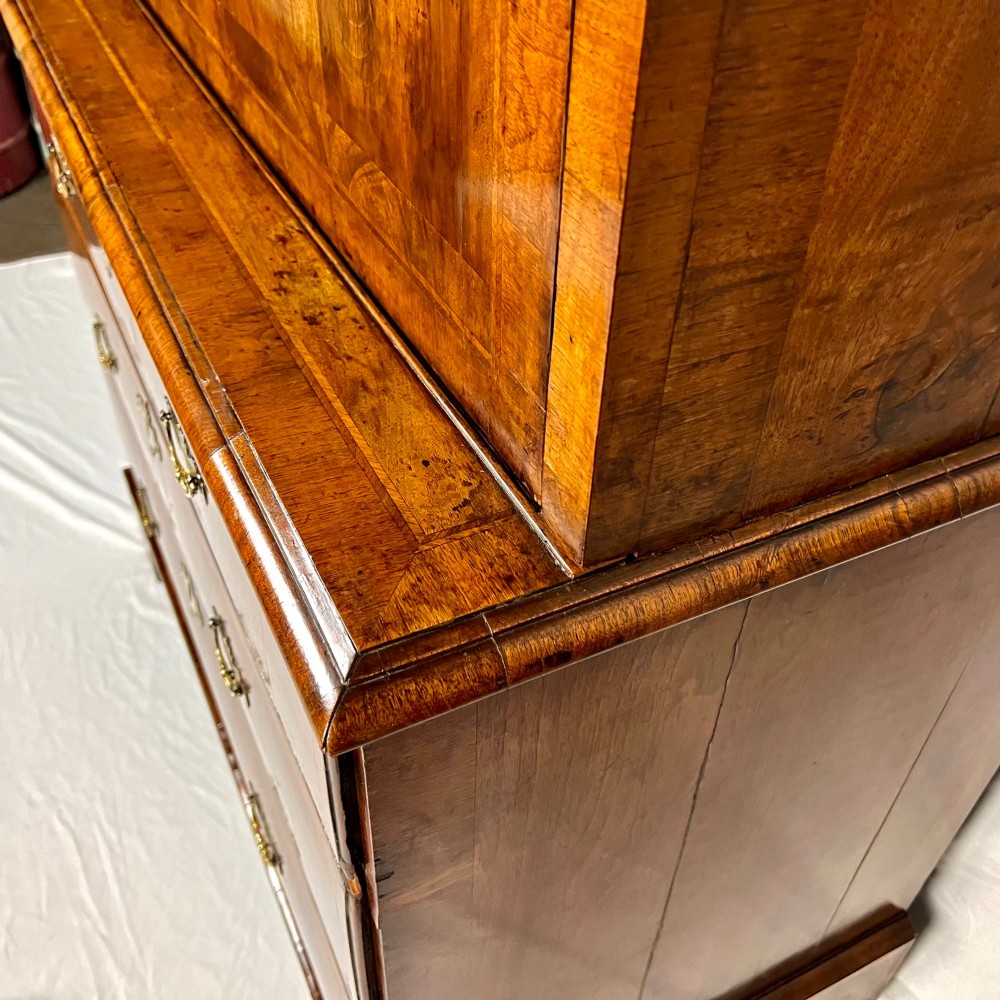 An eighteenth-century early Georgian figured walnut escritoire featuring an open fall-front revealing a detailed fitted interior above a lower chest of drawers with brass handles. View XII