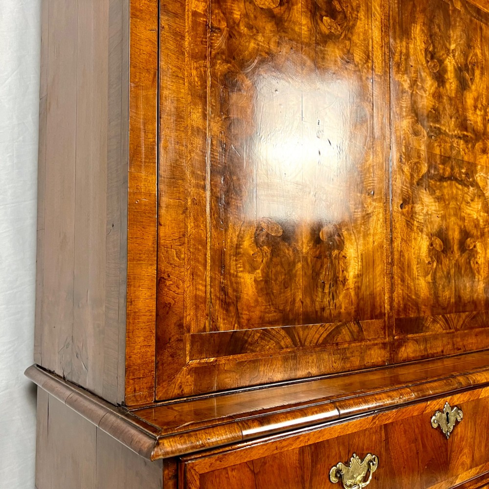 An eighteenth-century early Georgian figured walnut escritoire featuring an open fall-front revealing a detailed fitted interior above a lower chest of drawers with brass handles. View XIII