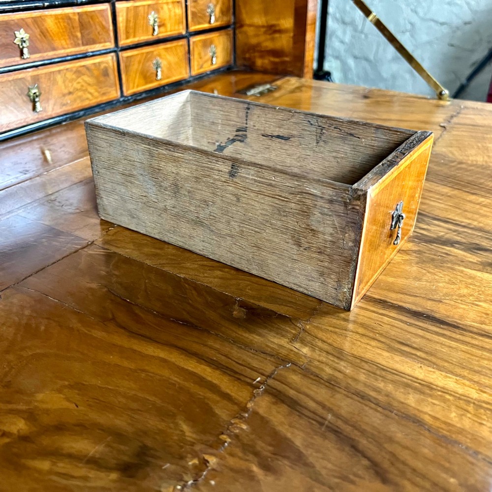 An eighteenth-century early Georgian figured walnut escritoire featuring an open fall-front revealing a detailed fitted interior above a lower chest of drawers with brass handles. View XIV