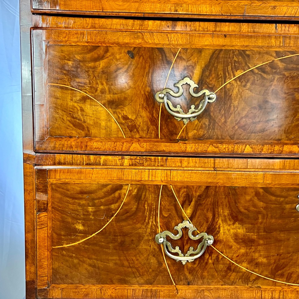 A tall George II two-part walnut chest on chest featuring figured burr walnut drawer fronts with line inlay, brass swan-neck handles, and bracket feet. View VI