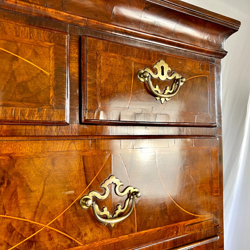 A tall George II two-part walnut chest on chest featuring figured burr walnut drawer fronts with line inlay, brass swan-neck handles, and bracket feet. View VIII
