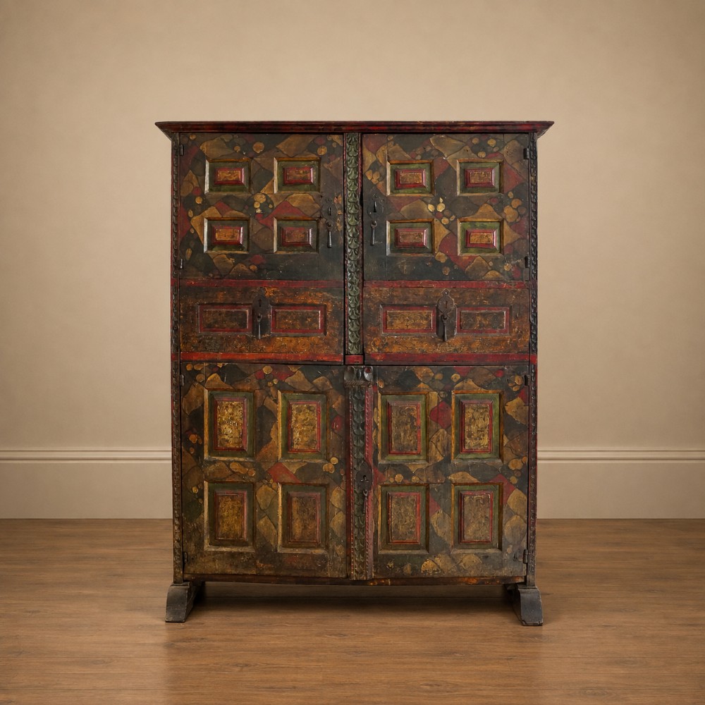 A tall seventeenth-century Spanish oak press cupboard featuring double upper and lower doors decorated with geometric raised panels and painted polychrome geometric patterns.