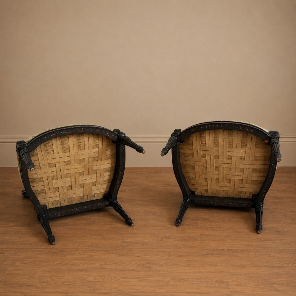 A pair of ebonised beech Louis XVI Revival salon armchairs featuring carved frames, fluted legs, padded armrests, and tapestry upholstery, accompanied by matching footstools. View XV