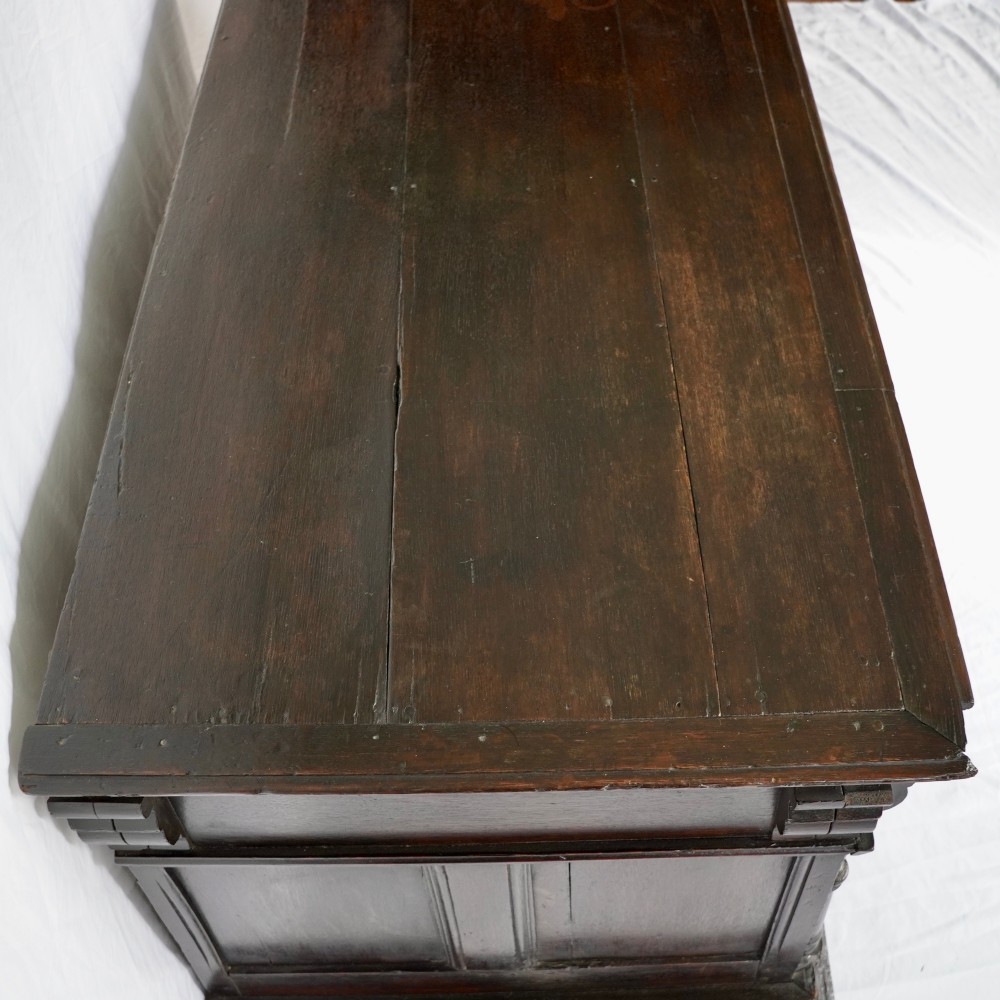 A dark oak 17th-century style chest of drawers featuring geometric timber inlay along the top frieze, applied mouldings, and brass drop handles. View XI