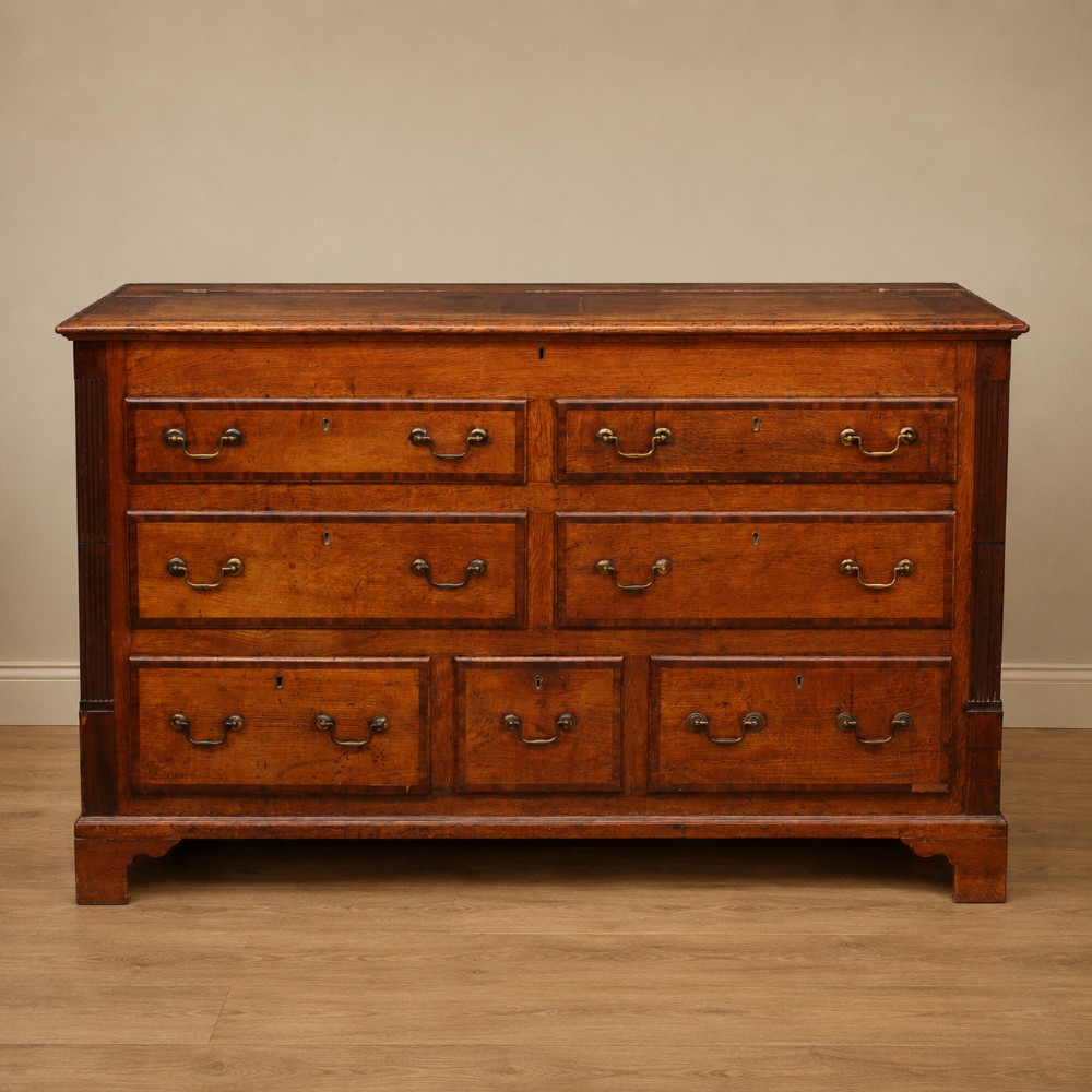 A Georgian oak and mahogany crossbanded Lancashire mule chest with brass handles and bracket feet.