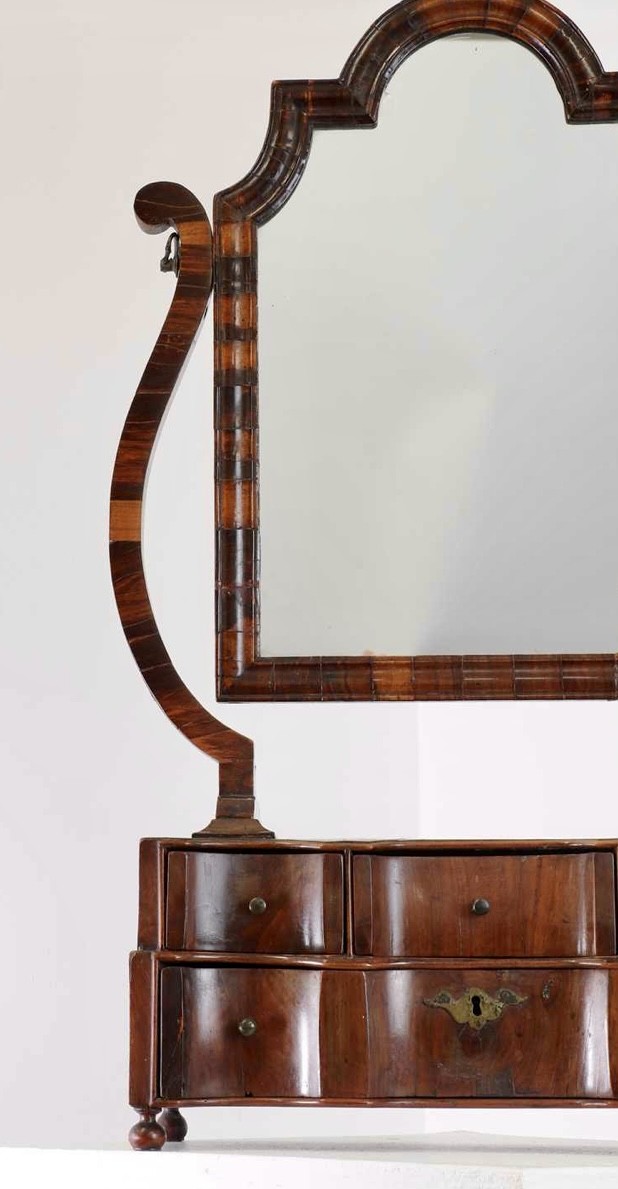 An antique Queen Anne walnut and laburnum toilet mirror featuring an arched cross-banded frame above a serpentine base with miniature drawers. View III
