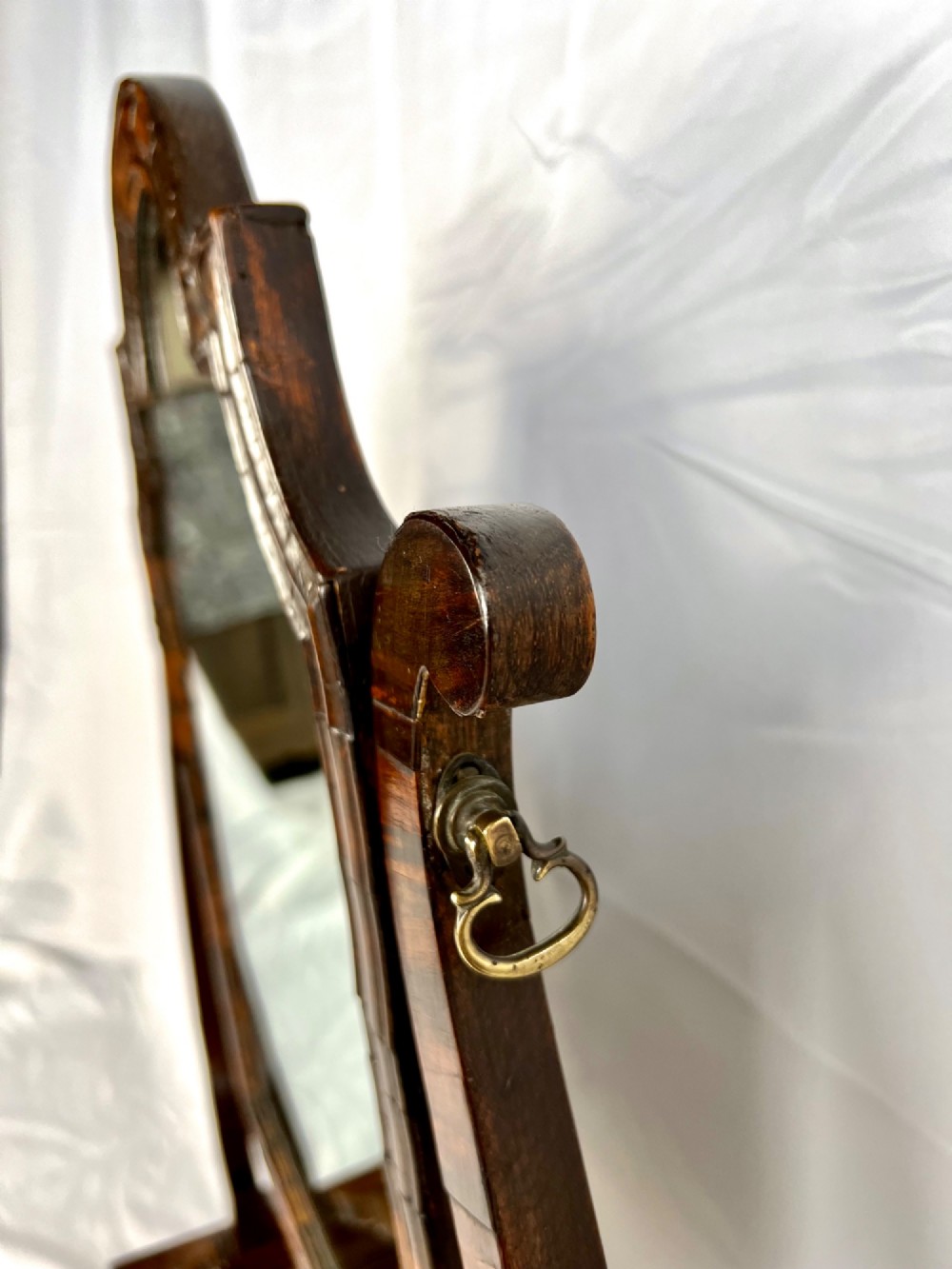 An antique Queen Anne walnut and laburnum toilet mirror featuring an arched cross-banded frame above a serpentine base with miniature drawers. View IX