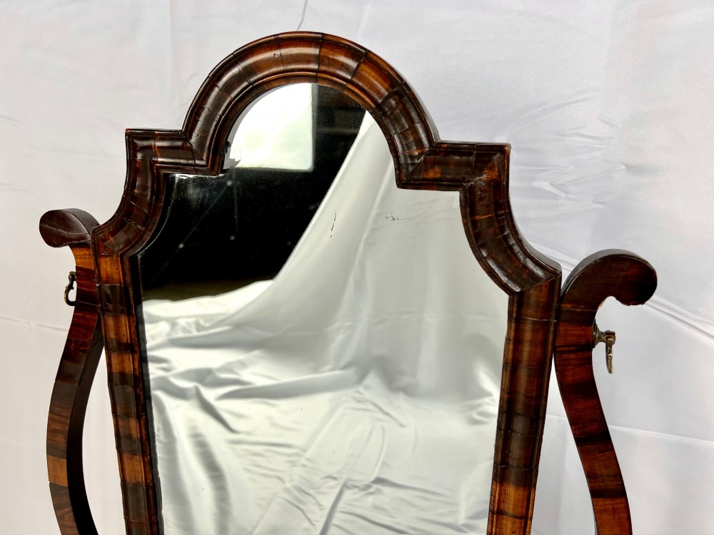 An antique Queen Anne walnut and laburnum toilet mirror featuring an arched cross-banded frame above a serpentine base with miniature drawers. View X