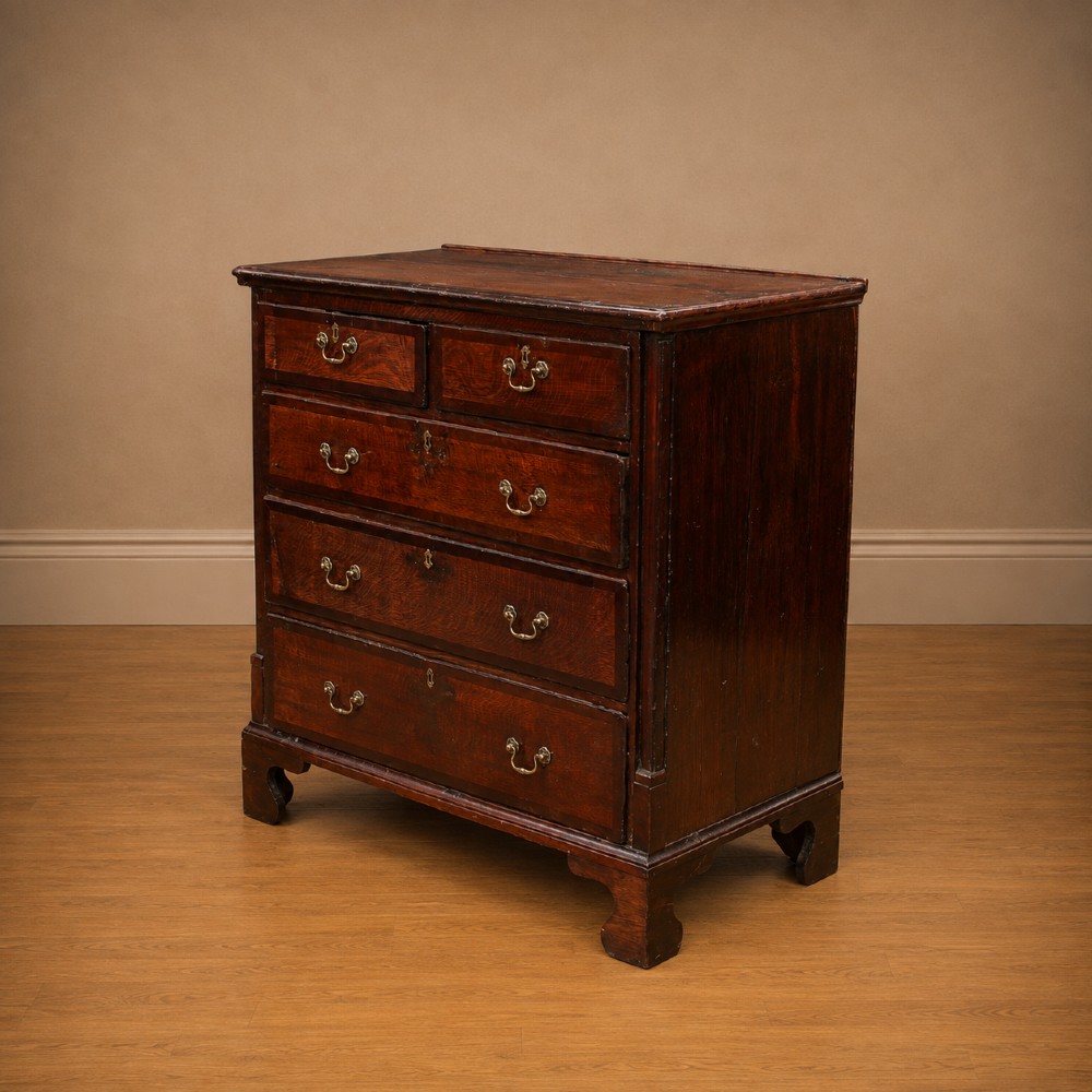 A Georgian dark oak chest of drawers featuring two short drawers over three long drawers with mahogany crossbanding and brass swan-neck handles. View IV