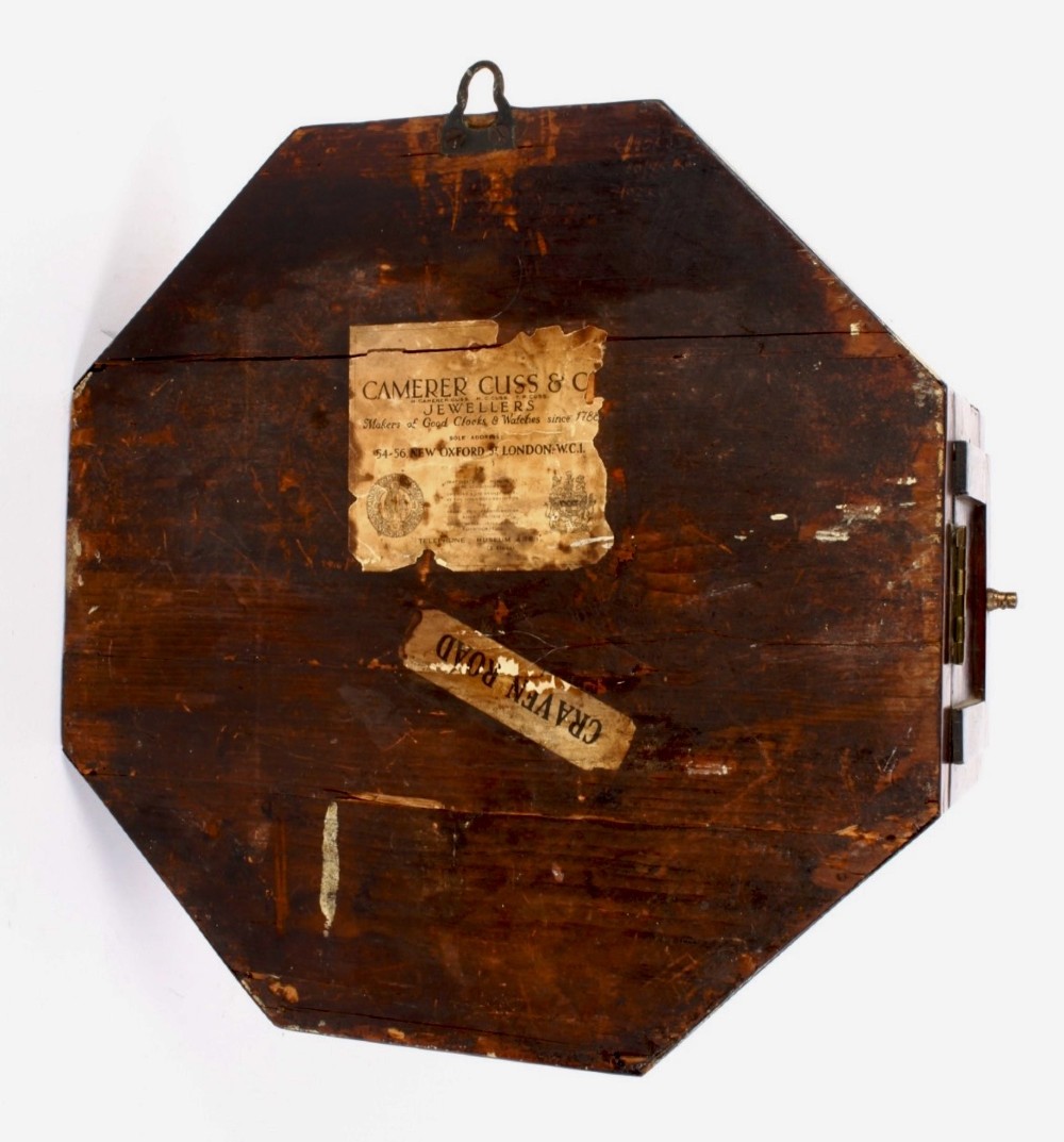 An octagonal Regency period wall clock in dark mahogany wood with intricate brass foliate inlay and a white dial featuring Roman numerals. View VI