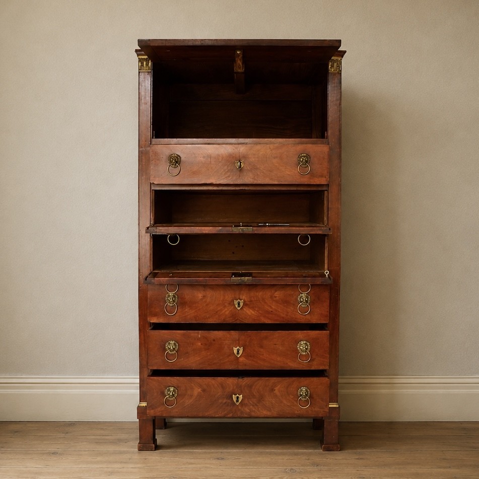 A 19th-century French Empire walnut secretaire cabinet featuring multiple drawers, brass lion-head ring handles, and fall-front writing compartments.