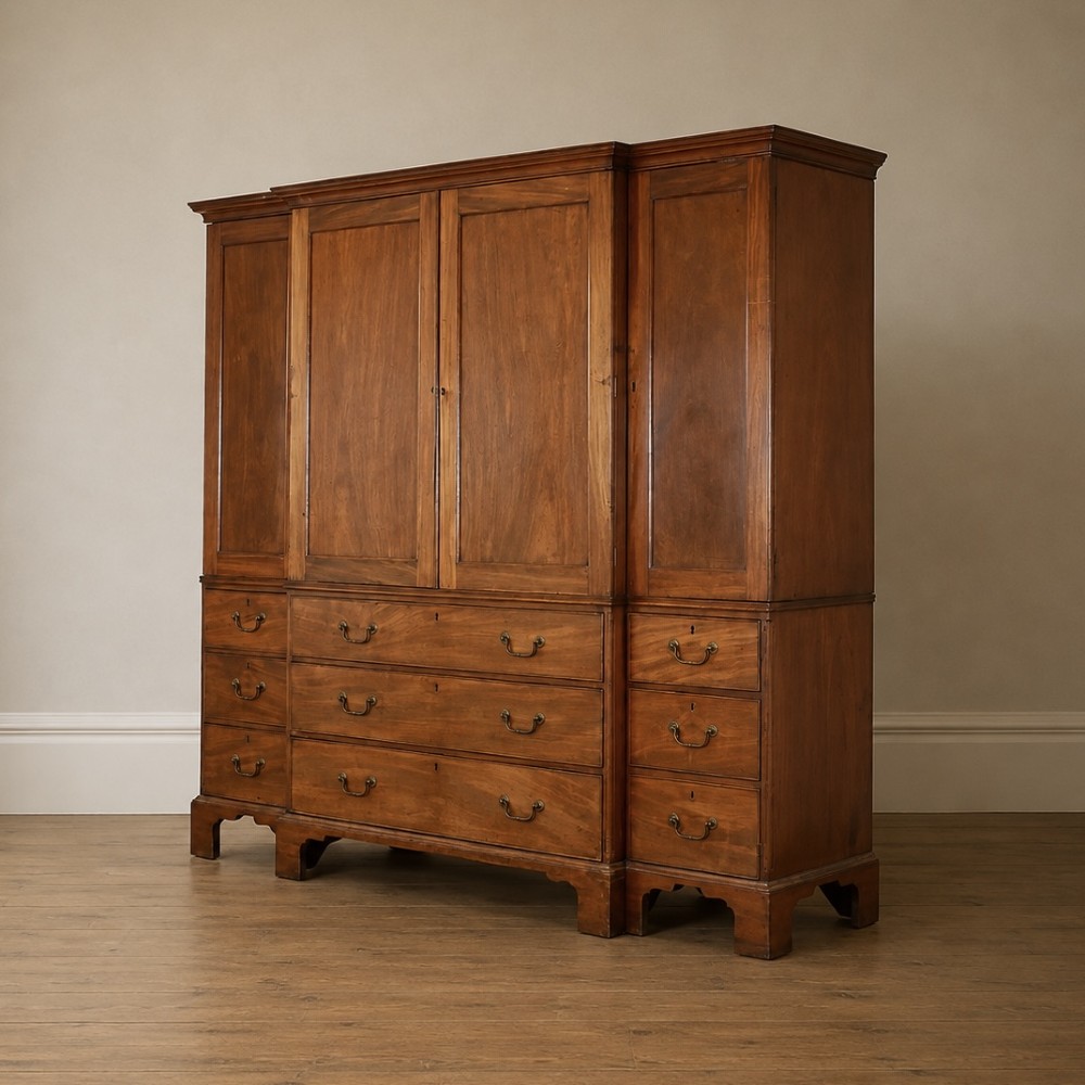 A large George III mahogany breakfront linen press wardrobe featuring central panelled doors above drawers, flanked by side cupboards on bracket feet. View X