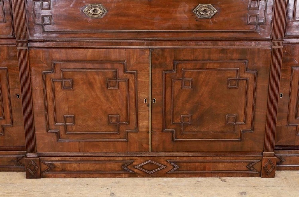 A large George IV mahogany breakfront library bookcase featuring gothic astragal glazed upper doors above drawers and cupboard doors with geometric moulding. View IV