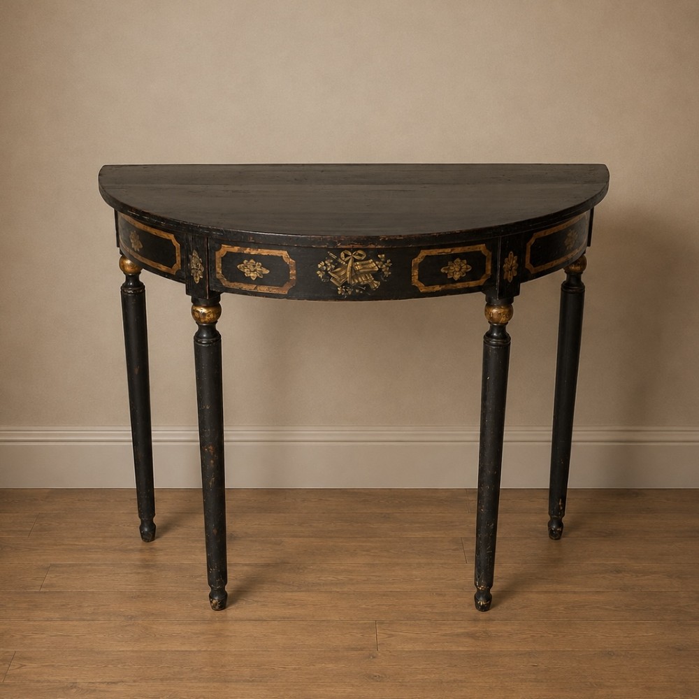 A Regency period semi-circular console table painted black with gold-gilded classical panel motifs and four slender turned legs.
