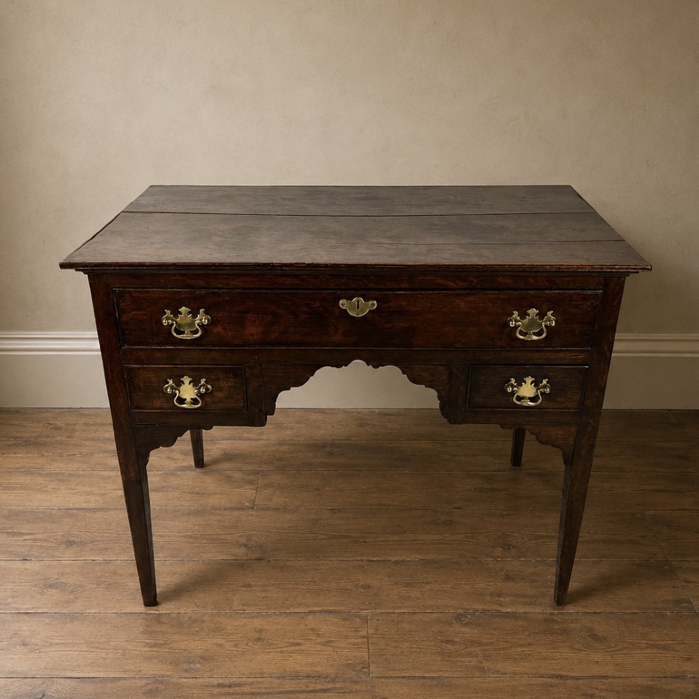 An 18th-century Georgian dark oak lowboy side table featuring three drawers with brass handles, a shaped apron, and slender square legs. View III