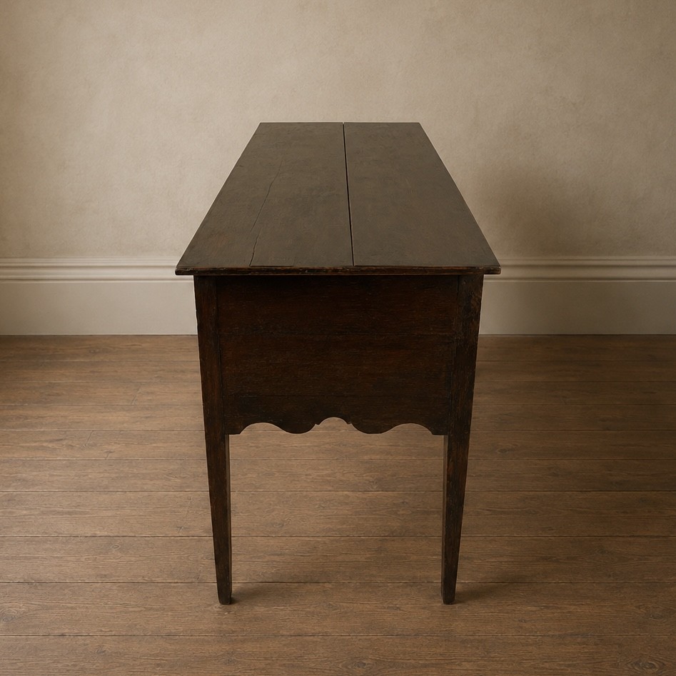 An 18th-century Georgian dark oak lowboy side table featuring three drawers with brass handles, a shaped apron, and slender square legs. View VI