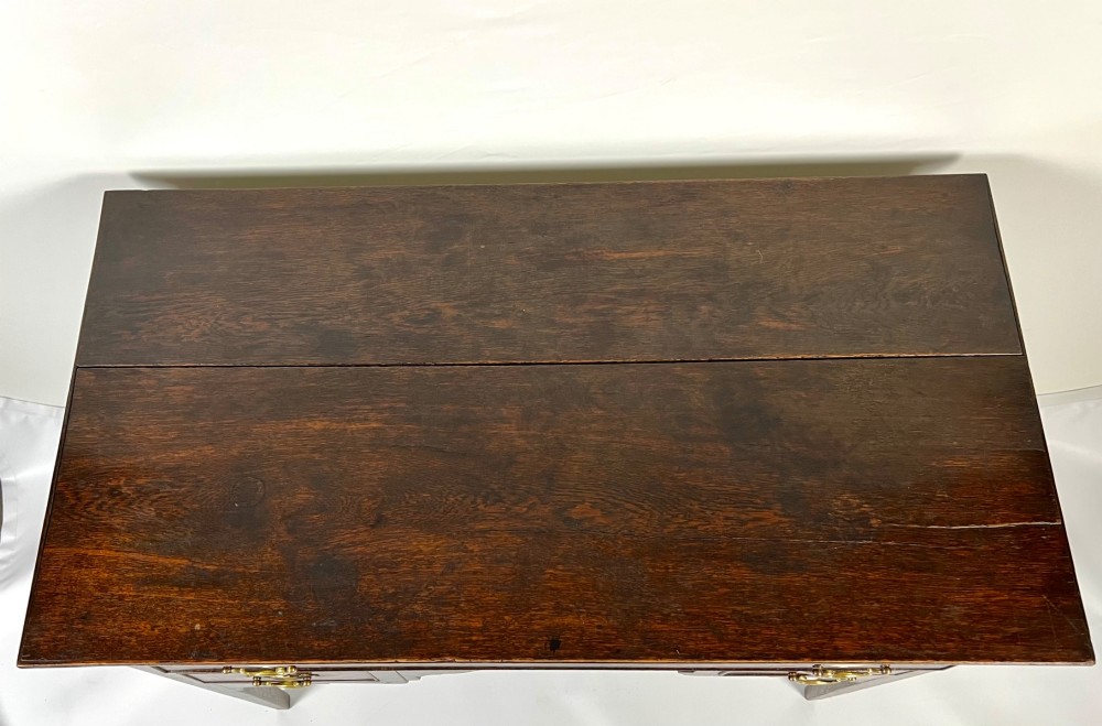 An 18th-century Georgian dark oak lowboy side table featuring three drawers with brass handles, a shaped apron, and slender square legs. View VII
