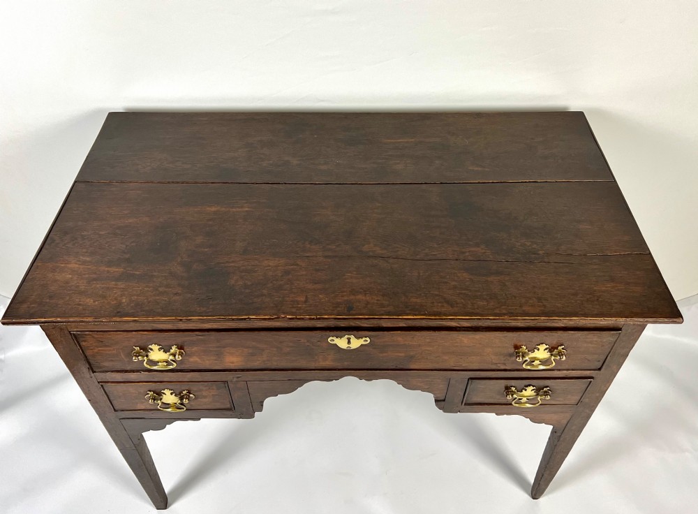An 18th-century Georgian dark oak lowboy side table featuring three drawers with brass handles, a shaped apron, and slender square legs. View VIII