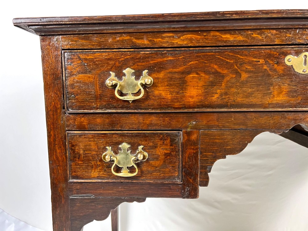 An 18th-century Georgian dark oak lowboy side table featuring three drawers with brass handles, a shaped apron, and slender square legs. View IX