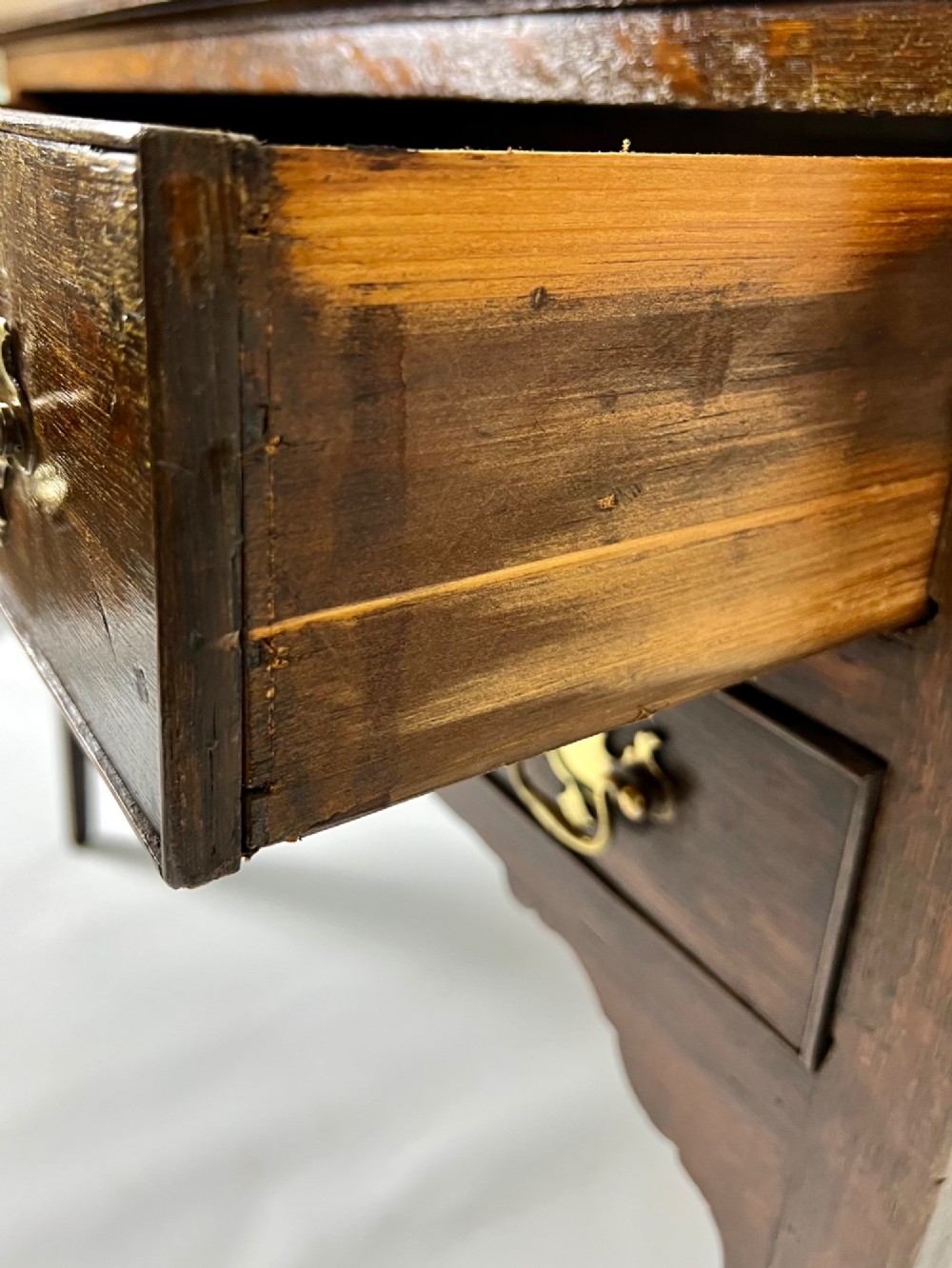 An 18th-century Georgian dark oak lowboy side table featuring three drawers with brass handles, a shaped apron, and slender square legs. View XI