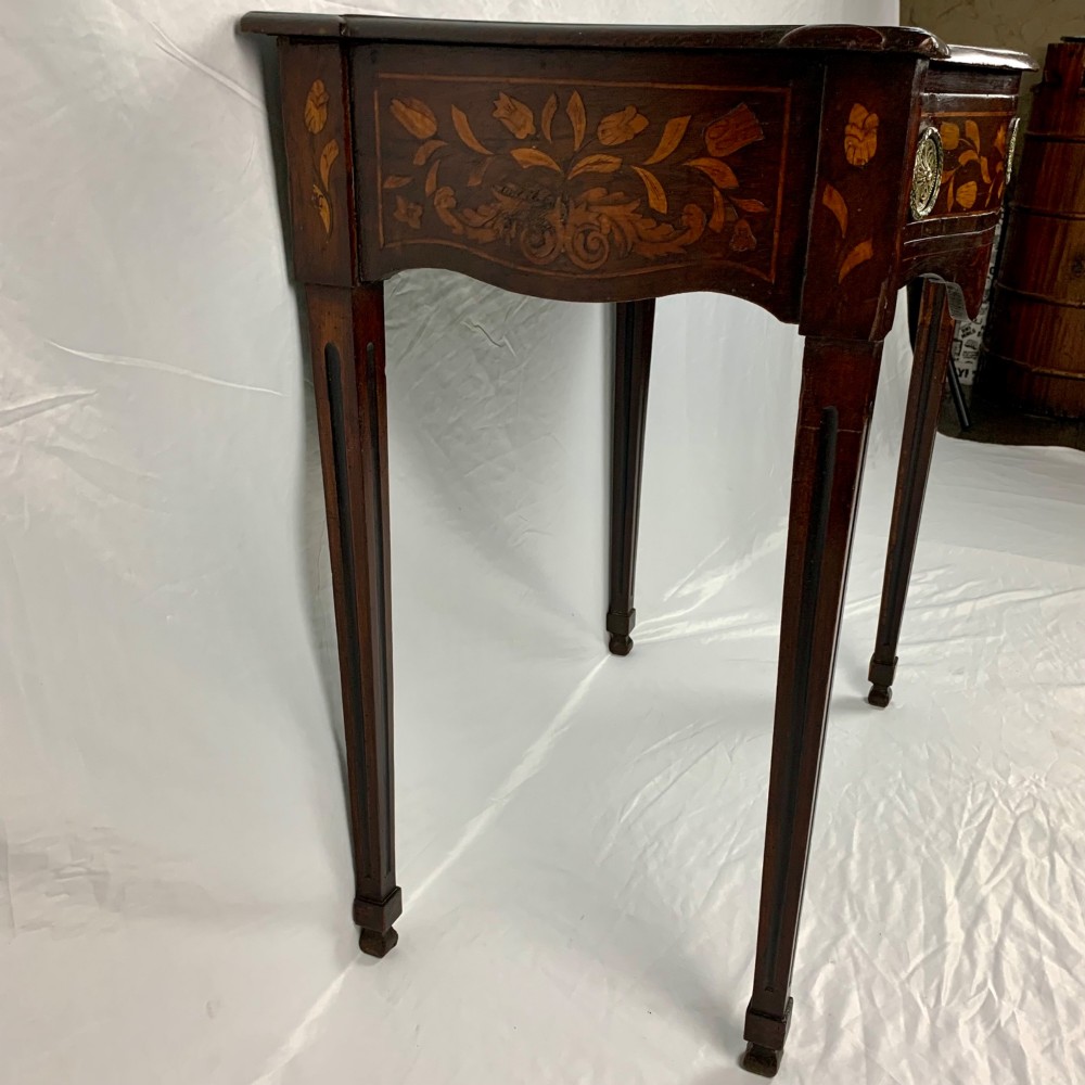 An 18th-century Dutch walnut side table featuring a serpentine front, floral marquetry inlay, a single drawer, and four square tapered legs. View VI