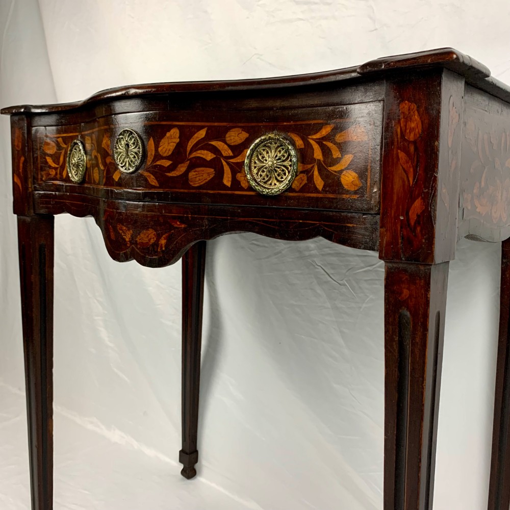 An 18th-century Dutch walnut side table featuring a serpentine front, floral marquetry inlay, a single drawer, and four square tapered legs. View VIII