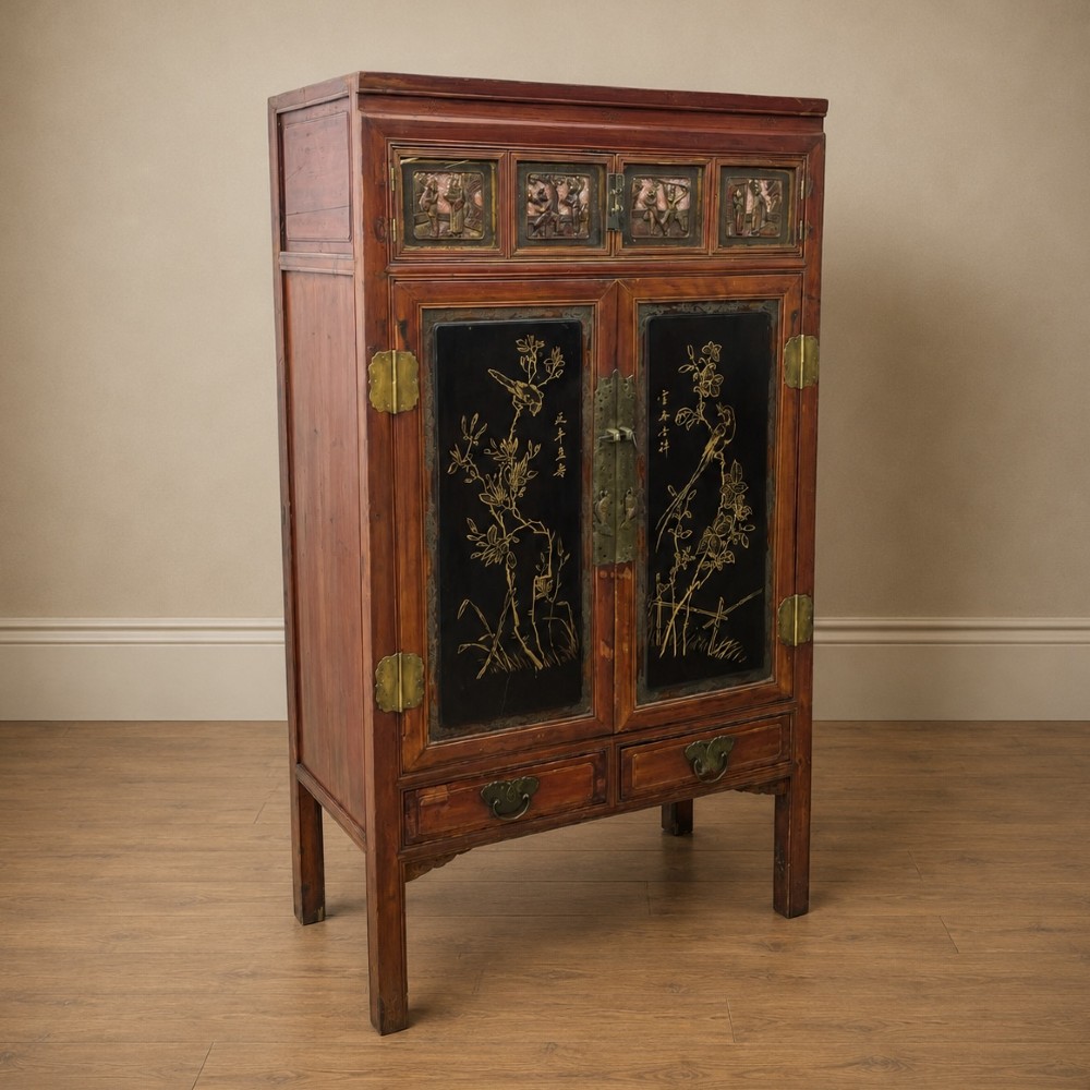 A late 19th-century Chinese red and black lacquer cabinet with double doors decorated with bird and botanical panels above two base drawers. View V