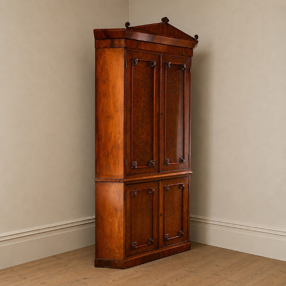 A tall, two-tier William IV corner cupboard crafted from dark plum pudding mahogany, featuring panelled double doors on both top and bottom sections with carved detail and a pediment top. View XIV