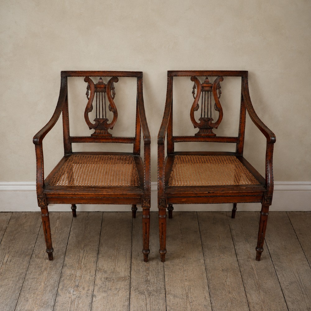 A matching pair of 19th-century Regency style mahogany armchairs featuring carved lyre back splats and woven cane seats. View XV
