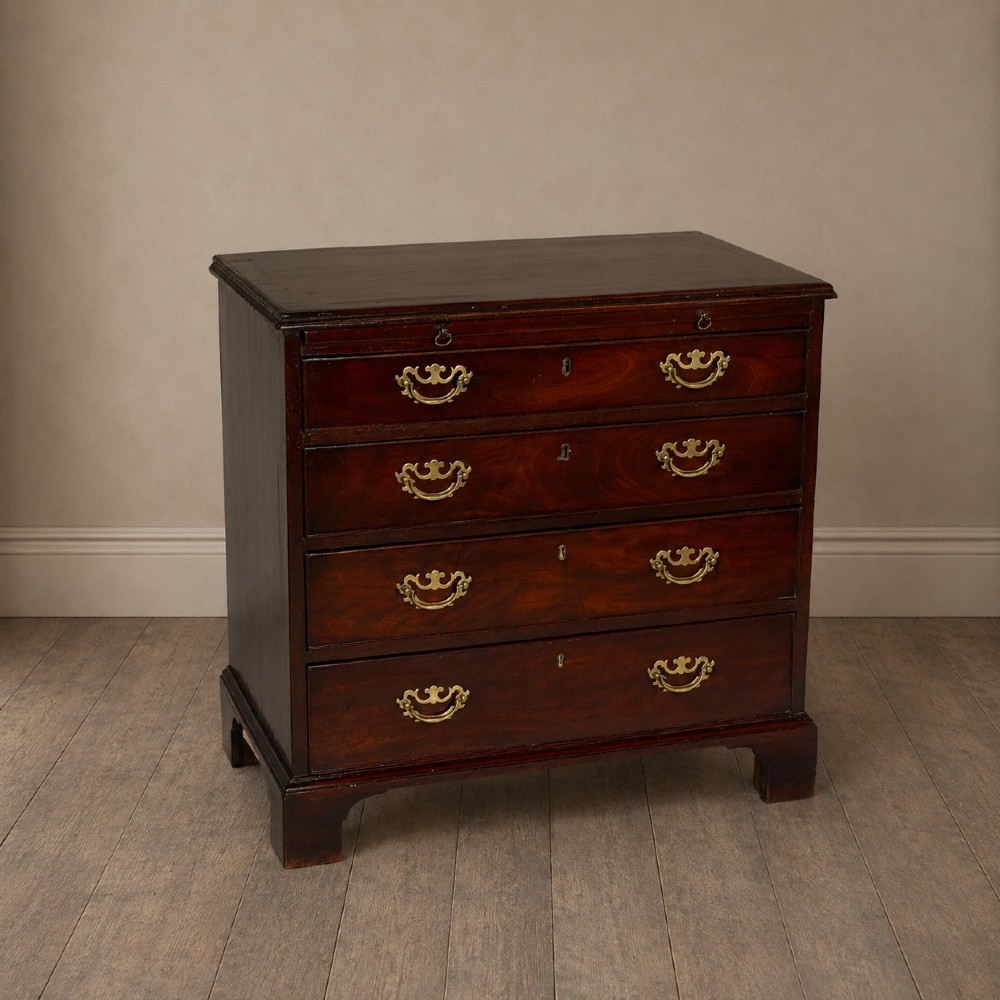 A George III flame mahogany bachelors chest of drawers featuring four graduated drawers, a pull-out brushing slide, ornate brass handles, and bracket feet. View XIII