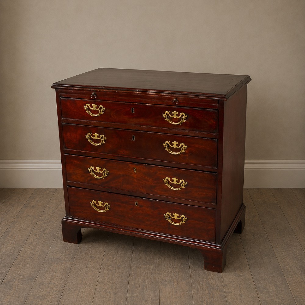A George III flame mahogany bachelors chest of drawers featuring four graduated drawers, a pull-out brushing slide, ornate brass handles, and bracket feet. View XIV