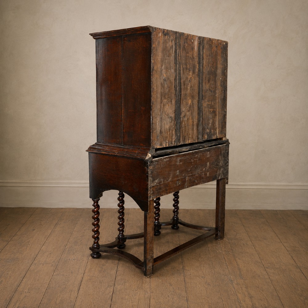 A George I period figured walnut chest on stand featuring engraved brass escutcheons and six barley-twist legs. View VII