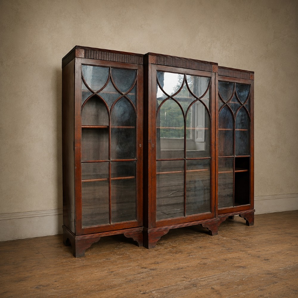 A large Victorian dark mahogany breakfront glazed bookcase featuring three doors with Gothic arch astragal glazing bars and a fluted cornice. View XIII