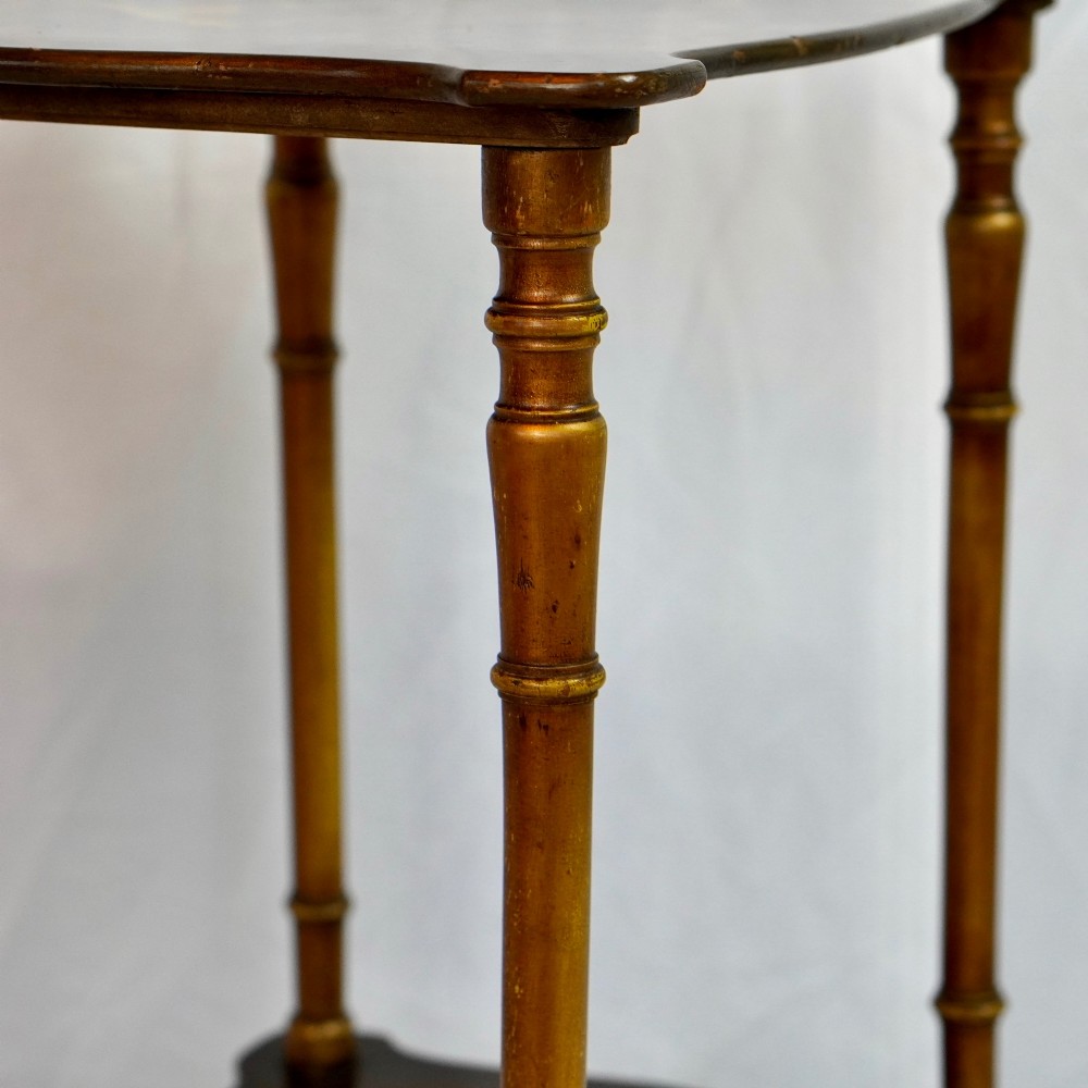 A two-tier continental side table featuring hand-painted figural scenes on shaped wooden surfaces, supported by turned gilt legs. View VII