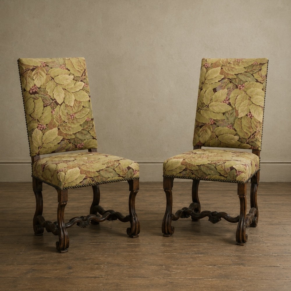 A pair of late 19th-century French walnut side chairs with high upholstered backs in a leafy green tapestry fabric and carved curved legs.