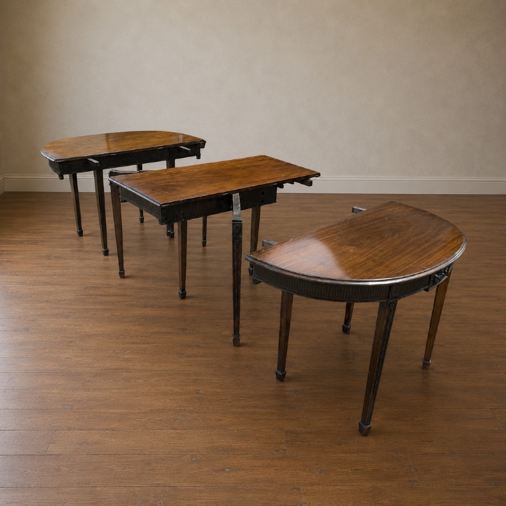 A long late George III mahogany extending dining table with D-shaped end sections, fluted friezes, carved paterae, and square tapered legs. View IX