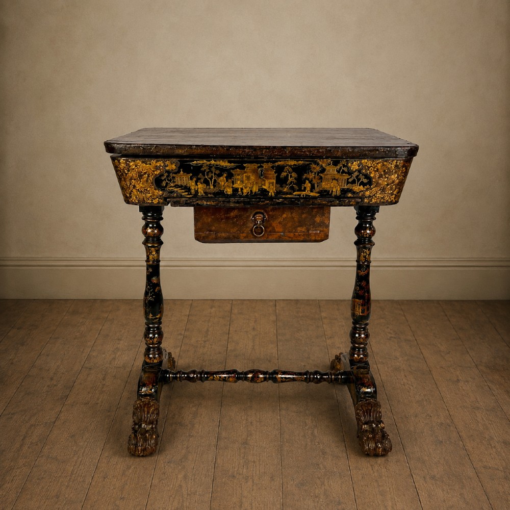 A Regency era black lacquered work table featuring detailed gold chinoiserie motifs, turned legs, a stretcher base, and carved paw feet.