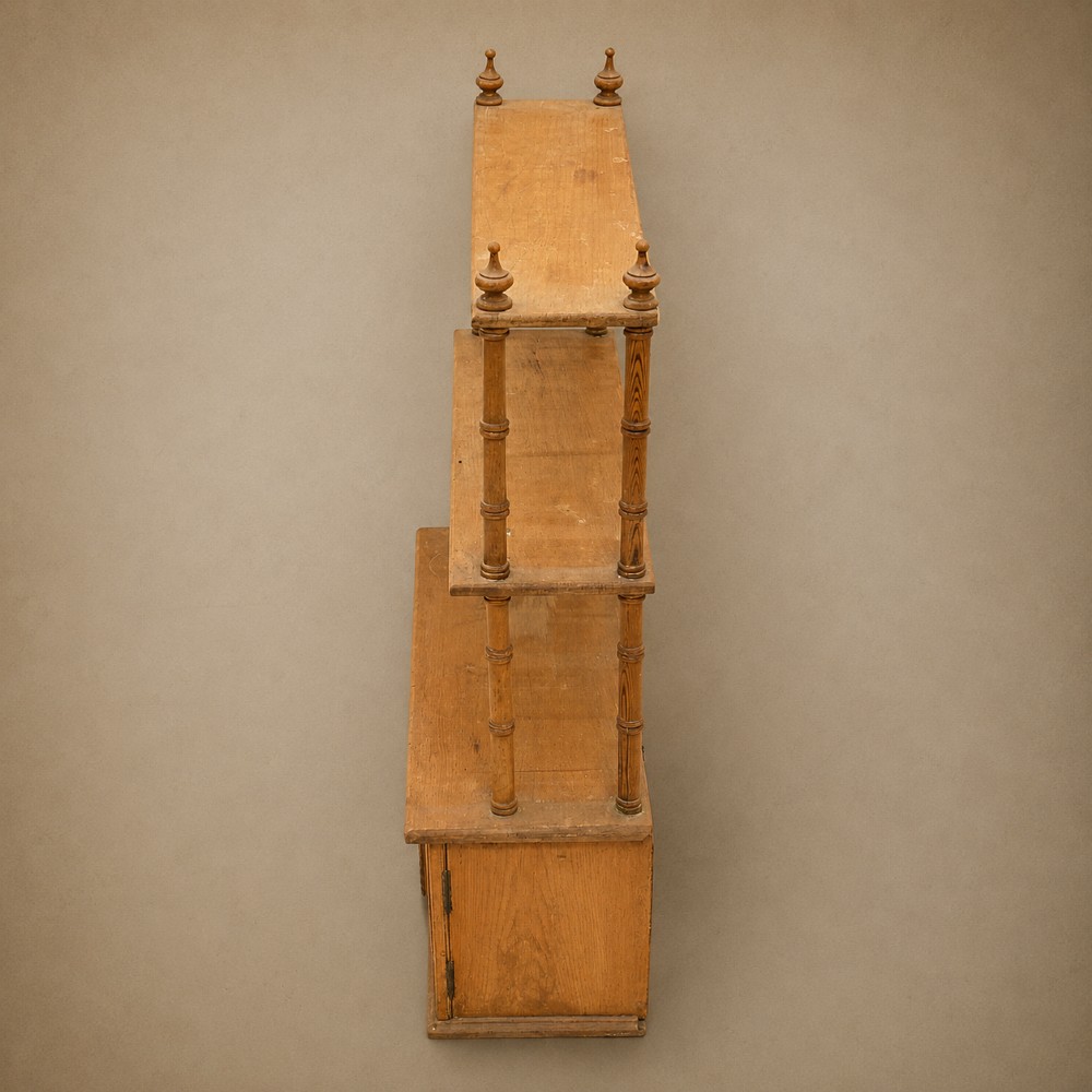 A 19th-century wall-mounted pine rack featuring two open upper shelves supported by turned spindles with finials above an enclosed double-door cupboard. View VI