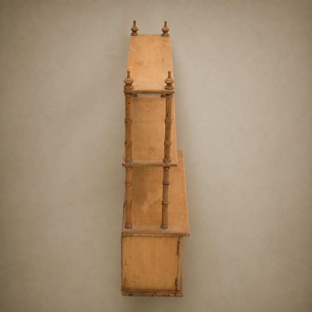 A 19th-century wall-mounted pine rack featuring two open upper shelves supported by turned spindles with finials above an enclosed double-door cupboard. View VII