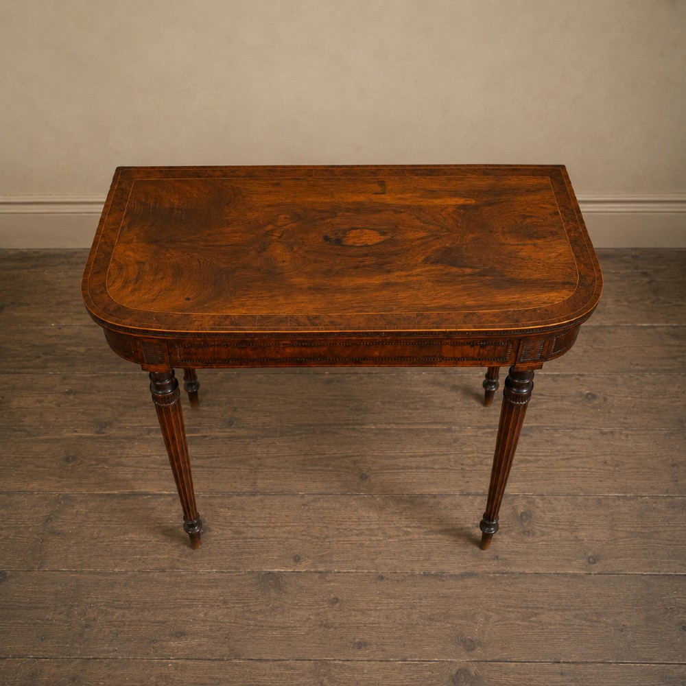 An antique Regency rosewood fold-over card table featuring burr yew crossbanding, a rectangular top with rounded corners, and slender fluted tapered legs. View VII